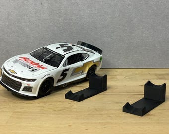 Può includere: Un'auto da corsa NASCAR bianca con il numero 5 e il logo Hendrick Motorsports. L'auto è su un supporto di esposizione nero.