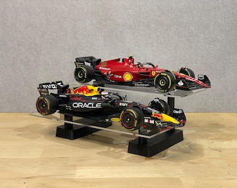 May include: Two Formula 1 race cars on a black display stand. The top car is red with the number 55 and the text "Oracle" and "Bybit". The bottom car is black with the text "Red Bull" and "Oracle".
