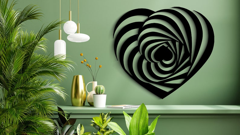 May include: Black metal heart wall art with a striped, optical illusion design. The heart is mounted on a green wall, with a shelf below holding decorative items and plants. The design creates a 3D effect.