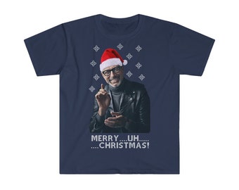 Puede incluir: Camiseta azul marino con un hombre sonriente con gorro de Papá Noel y gafas. La camiseta tiene el texto "MERRY...UH.....CHRISTMAS!" con gráficos de estrellas blancas. La camiseta es de manga corta y cuello redondo.