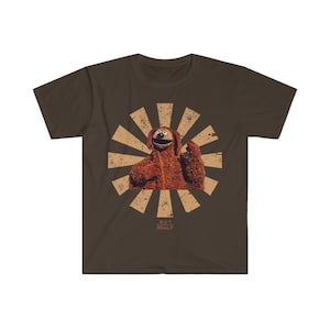 May include: A brown t-shirt with a retro-style graphic of a brown furry character with a big smile and a raised hand. The graphic is surrounded by a red and white sunburst design. The text "BOULIF" is written in red below the graphic.