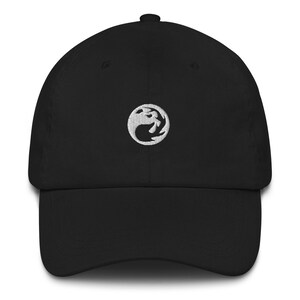 May include: A black baseball cap with a white embroidered logo of a dragon on a circle. The logo is centered on the front of the cap.