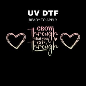 May include: A pink and green design with the text "GROW through what you GO through" and two hearts on either side of the text. The text is in a cursive font. The design is ready to apply using a UV DTF printer.
