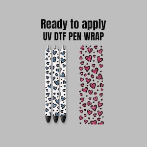 May include: Three white pens with a blue glitter heart pattern are ready to be applied with a UV DTF pen wrap. A sheet of the wrap is shown with a pink glitter heart pattern.