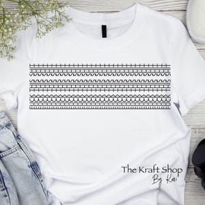 May include: White t-shirt featuring a black geometric design across the chest. The design includes various patterns such as lines, waves, and triangles. The text "The Kraft Shop By Kari" is printed at the bottom.