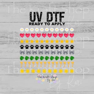 May include: A UV DTF ready to apply transfer sheet featuring eight horizontal rows of repeating icons: white daisies, pink hearts, yellow stars, black paw prints, grey bows, green monstera leaves, yellow drips, and yellow suns on a wood background.