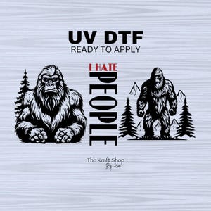 May include: Black and white Bigfoot graphic with the text "I HATE PEOPLE" and "UV DTF READY TO APPLY". The design features two Bigfoot illustrations, trees, and mountains. The Kraft Shop By Kate.
