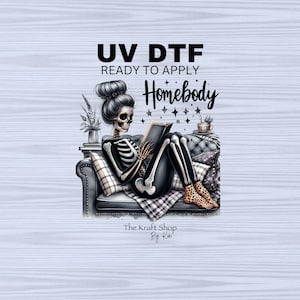 May include: A digital graphic featuring a skeleton reading a book while lounging on a sofa. The skeleton is wearing leopard print slippers and is surrounded by pillows and a blanket. Text reads "UV DTF Ready to Apply Homebody".