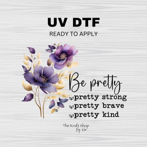 May include: A digital transfer design featuring a floral arrangement with purple flowers and gold leaves. The design includes the text "Be pretty, pretty strong, pretty brave, pretty kind". The text "The Kraft Shop By Kai" is also included.