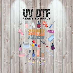 May include: A collection of nail art tools and products, including nail polish bottles, brushes, and a cuticle pusher, arranged on a wooden background. The text "UV DTF READY TO APPLY" and "SOMEBODY'S BOMB ASS NAILTECH" are displayed.