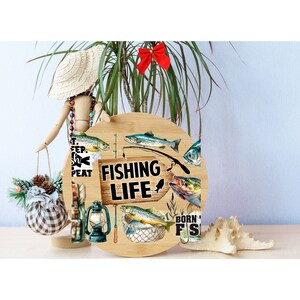 May include: A round wooden sign with a fishing theme. The sign features a fishing rod, a net, and several fish. The text on the sign reads "Fishing Life" and "Born to Fish".