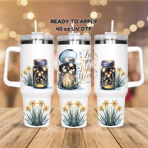 May include: Three white 40 oz UV DTF tumblers with handles and lids. Each tumbler features a design of a mason jar filled with glowing lights and flowers, with the text "Let your light bloom". Yellow daffodils are at the bottom.