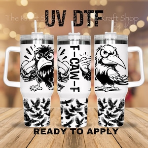 May include: Three white insulated tumblers with black crow illustrations and the text "F-CAW-F". The tumblers have white handles and lids with straws. The bottom of each tumbler features a pattern of black crow silhouettes. The words "READY TO APPLY" are at the bottom.
