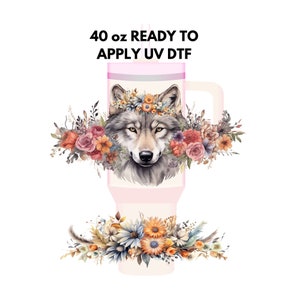 May include: A 40 oz. tumbler with a pink lid and handle, ready to apply UV DTF. The tumbler features a watercolor illustration of a wolf's head with a floral crown, surrounded by a floral design.