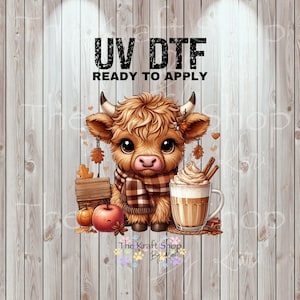 May include: A digital graphic featuring a cute Highland cow wearing a scarf, with a latte, pumpkins, and an apple. The text "UV DTF READY TO APPLY" is at the top. The Kraft Shop By Lori logo is at the bottom.