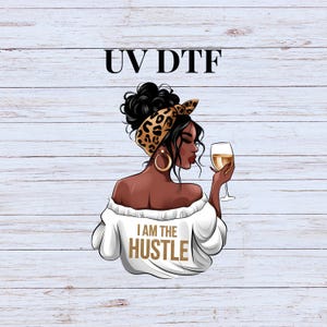 May include: Illustration of a woman with dark hair and skin, wearing a white off-the-shoulder top with the text "I AM THE HUSTLE". She has a leopard print headscarf and gold hoop earrings, holding a glass of wine. The image has the text "UV DTF" at the top.