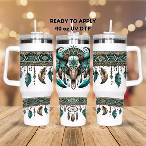 May include: Three 40 ounce stainless steel tumblers with a white background and a turquoise, brown, and gold design featuring a dream catcher, feathers, and a bull skull. The text "READY TO APPLY 40 oz UV DTF" is printed on the top of the image.