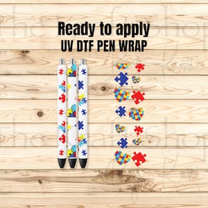 May include: Three white pens featuring a colorful puzzle piece pattern and a separate sheet of UV DTF pen wrap decals with heart and puzzle piece designs. The text "Ready to apply UV DTF PEN WRAP" is printed in black above the items.