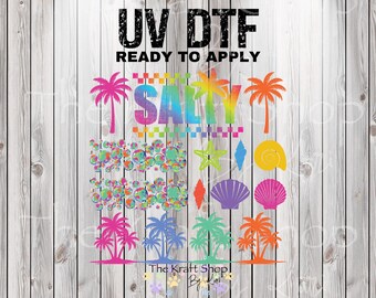 May include: UV DTF ready to apply graphic featuring the word "SALTY" in rainbow colors, palm trees, seashells, and other beach-themed elements. The Kraft Shop By Lori logo is at the bottom.