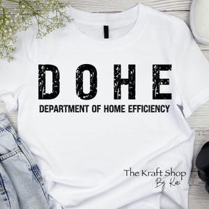 May include: White t-shirt with black text that reads "DOHE Department of Home Efficiency" and a small logo at the bottom that reads "The Kraft Shop By Kari".