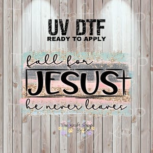 May include: A UV DTF transfer with the text "UV DTF READY TO APPLY". The design features the words "fall for JESUS he never leaves" in a black font, with a cross. The background has pastel colors and gold glitter.