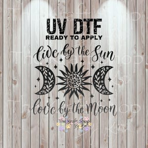 May include: Black UV DTF transfer with the text "UV DTF READY TO APPLY" and "Live by the Sun Love by the Moon". The design features a sun, two crescent moons, and stars. The Kraft Shop logo is at the bottom.