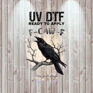 May include: UV DTF ready to apply transfer featuring a black raven perched on a branch with bare branches in the background. The raven is depicted with its beak open. The text "F-CAW-F" is above the raven.