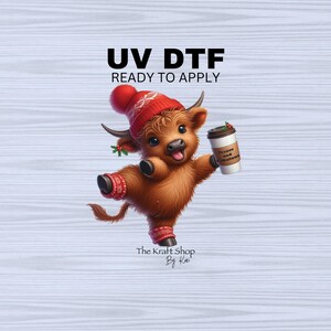 May include: A whimsical illustration of a Highland cow wearing a red knit hat and leg warmers, holding a coffee cup. The text "UV DTF READY TO APPLY" is at the top, with "The Kraft Shop By Kai" at the bottom.