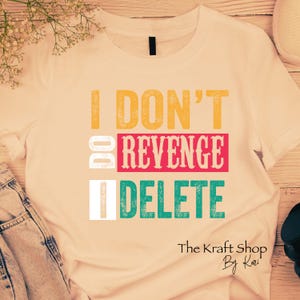 May include: Cream-colored t-shirt with the text "I DON'T DO REVENGE I DELETE" in yellow, red, and teal lettering. The Kraft Shop by Kari logo is at the bottom right.