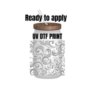 May include: A white tumbler with a wooden lid and a gray floral pattern. The tumbler has the text "UV DTF PRINT" on the front. The text "Ready to apply" is above the tumbler.