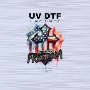 May include: A patriotic design featuring a cross with the American flag incorporated into the design. The words "UV DTF READY TO APPLY" are at the top, with "FAITH FAMILY FREEDOM" below the cross. The Kraft Shop By Kat is at the bottom.