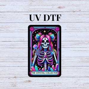 May include: A tarot card with a colorful illustration of a skeleton holding a crystal. The card is titled "The Crystal Collector" and has a black background with stars and crystals.