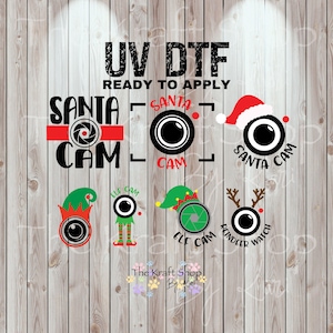May include: UV DTF ready to apply Christmas-themed designs. Includes Santa Cam, Elf Cam, and Reindeer Watch camera lens graphics with festive hats and antlers. The Kraft Shop logo is at the bottom.