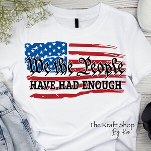May include: White t-shirt with a distressed American flag design and the text "We the People Have Had Enough". The Kraft Shop by Kari is printed in the bottom right corner.