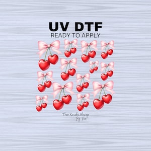 May include: A sheet of UV DTF transfer film with a design of red cherries with pink bows. The text "UV DTF READY TO APPLY" is at the top of the sheet. The text "The Kraft Shop By Kai" is at the bottom of the sheet.