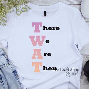 May include: White t-shirt with the text "There We Are Then" in a vertical column. The letters are in a gradient of pink, orange, and yellow. The text "The Kraft Shop By Kari" is in the bottom right corner.