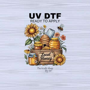 May include: A digital transfer design featuring a wooden crate filled with honey jars, a beehive, and sunflowers. The crate has a sign that reads "Local Honey". The design also includes a bee and the text "UV DTF Ready to Apply" and "The Kraft Shop By Kai".