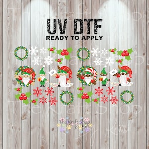 May include: UV DTF Christmas-themed transfers with elves, Santa, wreaths, snowflakes, and holly berries. The transfers are ready to apply and feature the text "UV DTF READY TO APPLY". The Kraft Shop by Lori logo is at the bottom.