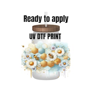 May include: A white tumbler with a wooden lid and a straw. The tumbler has a gold and blue honeycomb design with white daisies and bees. The text "UV DTF PRINT" is printed on the tumbler. The text "Ready to apply" is printed above the tumbler.