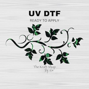 May include: A black and white graphic design of a leafy vine with the text "UV DTF READY TO APPLY" and "The Kraft Shop By Kari" on a white woodgrain background.