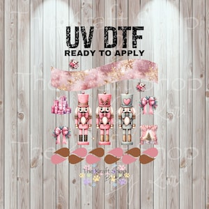 May include: UV DTF ready to apply transfer sheet featuring pink and gold Christmas nutcrackers, bows, and gift boxes. The design includes the text "UV DTF READY TO APPLY" and "The Kraft Shop By Kim" at the bottom.