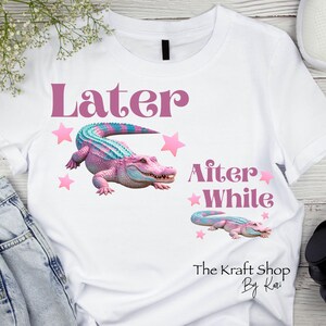 May include: White t-shirt featuring a pink and teal alligator design with the words "Later After While" and pink stars. The Kraft Shop By Kari is printed at the bottom.