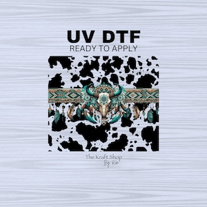 May include: UV DTF ready to apply transfer design featuring a black and white cowhide pattern with a turquoise and gold tribal design and a skull with feathers. The text "The Kraft Shop By Kai" is at the bottom of the design.