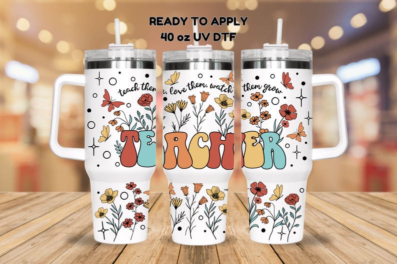 May include: Three 40 ounce stainless steel tumblers with a white background and floral designs. The tumblers have a handle and a straw. The text "teach them, love them, watch them grow" and "TEACHER" are printed on the tumblers.