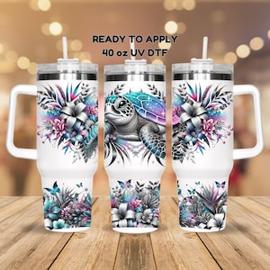 May include: Three 40 ounce stainless steel tumblers with lids and handles. The tumblers are white with a floral design and a sea turtle with a galaxy shell. The text "READY TO APPLY 40 oz UV DTF" is printed on the top of the image.