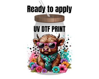 May include: A white tumbler with a brown lid and a straw. The tumbler has a UV DTF print of a cartoon Highland cow wearing pink sunglasses and a blue and white scarf. The cow is surrounded by colorful flowers.