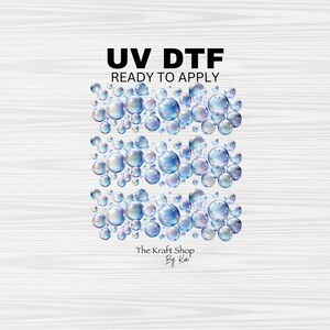 May include: UV DTF ready to apply transfer featuring a design of iridescent bubbles. The bubbles are clustered in three horizontal rows. The text "UV DTF READY TO APPLY" is in black, and the shop name "The Kraft Shop By Kai" is at the bottom.