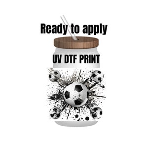 May include: A white can with a brown lid and a straw sticking out of the top. The can has a black and white graphic of soccer balls with black paint splatters. The text "UV DTF PRINT" is printed on the can. The text "Ready to apply" is printed above the can.