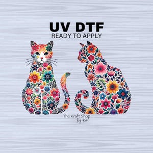 May include: Two colorful cats with floral patterns, sitting side-by-side. The text "UV DTF READY TO APPLY" is above the cats. The text "The Kraft Shop By Kai" is below the cats.