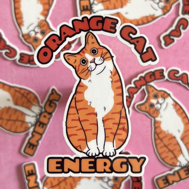 Peut inclure: Autocollant "&Eacute;nergie du chat orange" avec un chat orange et blanc dessin&eacute;. Le chat est assis et regarde sur le c&ocirc;t&eacute;. L'autocollant est &eacute;crit "&Eacute;nergie du chat orange" en orange gras.